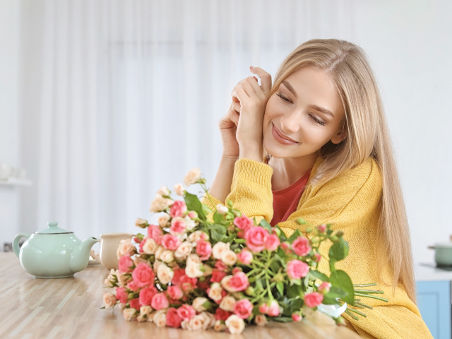 Молодая блондинка с букетом роз на столе
