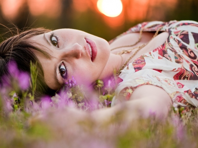 Молодая кареглазая девушка лежит на траве