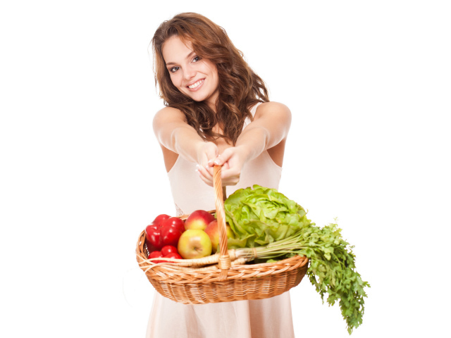 Молодая девушка с корзиной овощей и фруктов на белом фоне