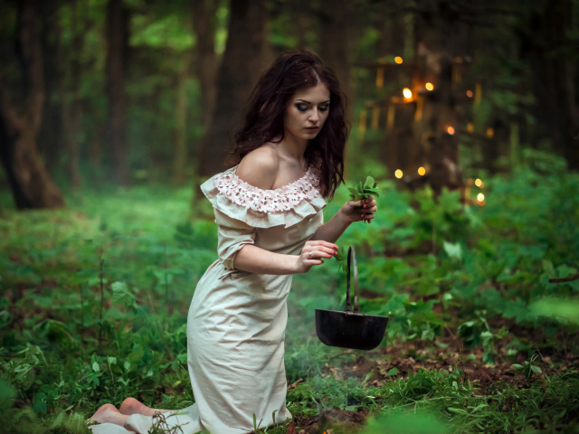 Молодая девушка колдунья варит зелье в лесу