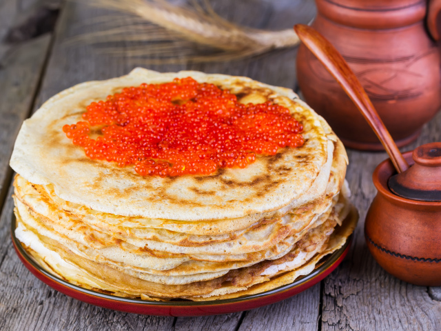 Стопка блинов с красной икрой на деревянном столе угощение на Масленицу