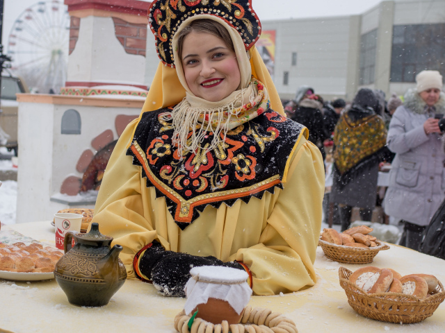 Красивая молодая девушка с угощениями на Масленицу 2018