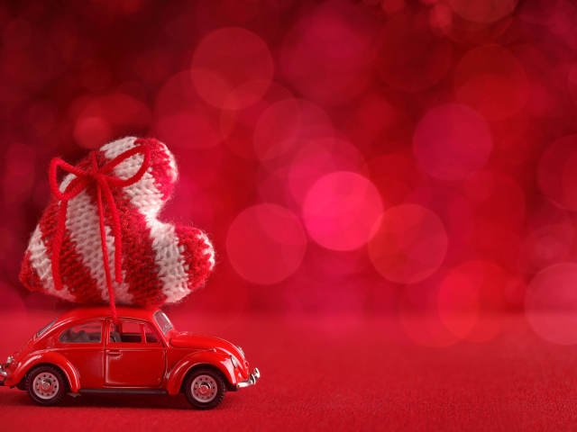 Красная игрушечная машинка везет с сердечко на розовом фоне, фон для открытки на День Святого Валентина