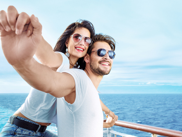 Влюбленная пара держится за руки на фоне моря