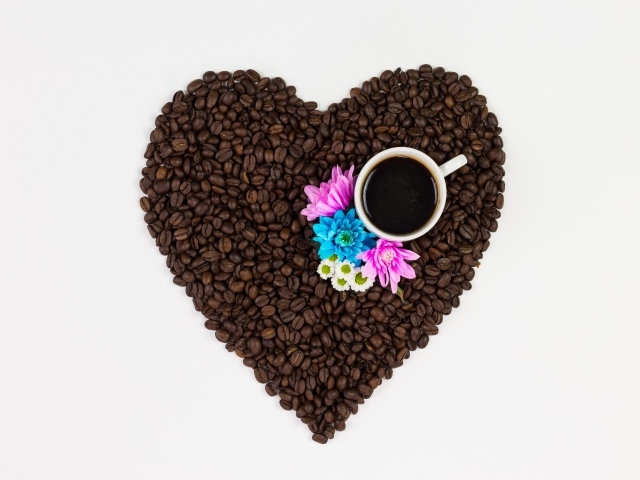 Сердце из кофейных зерен с чашкой на белом фоне