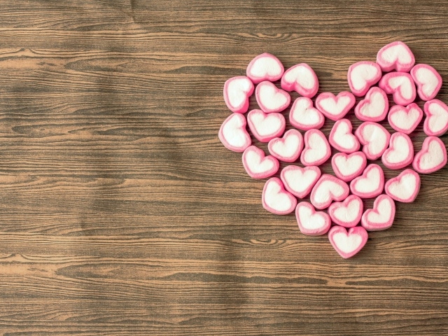 Сердце из конфет в форме сердца на деревянном столе