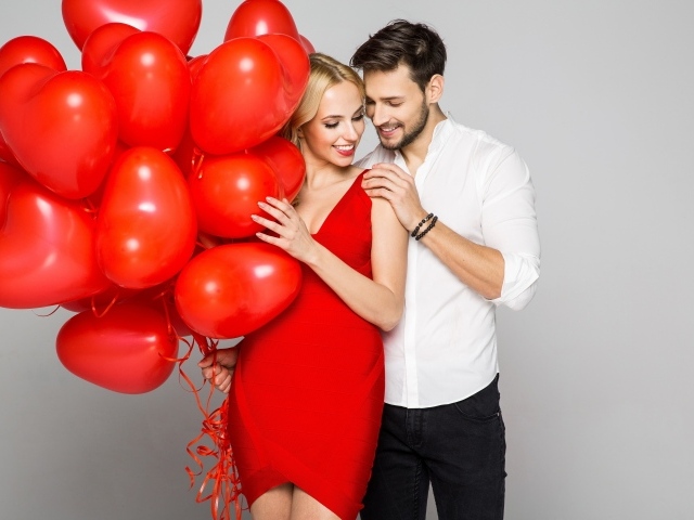 Влюбленная пара с красными воздушными шарами в форме сердца