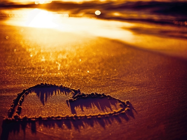 Нарисованное сердце на песке в лучах солнца