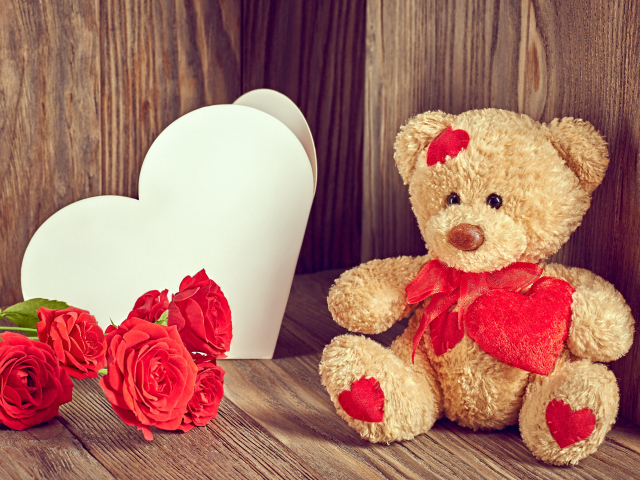 Плюшевый медведь с большим белым бумажным сердцем и красными розами