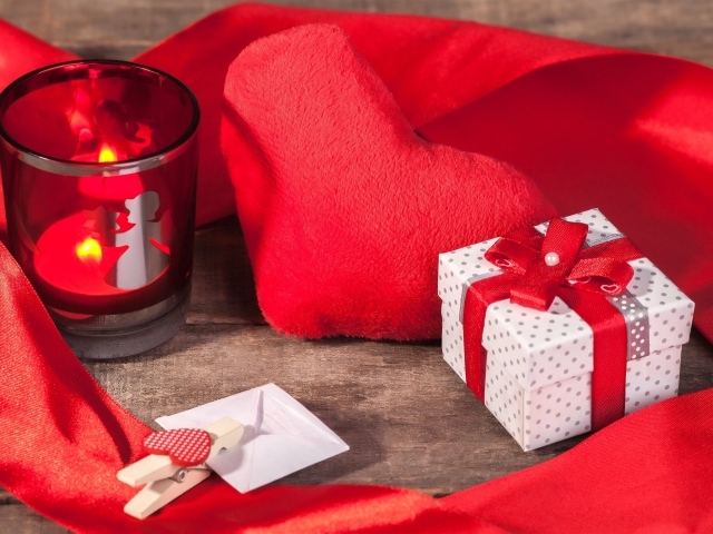 Мягкое красное сердце на столе с подарком и зажженной свечей