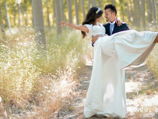 Парень жених держит на руках невесту в белом платье