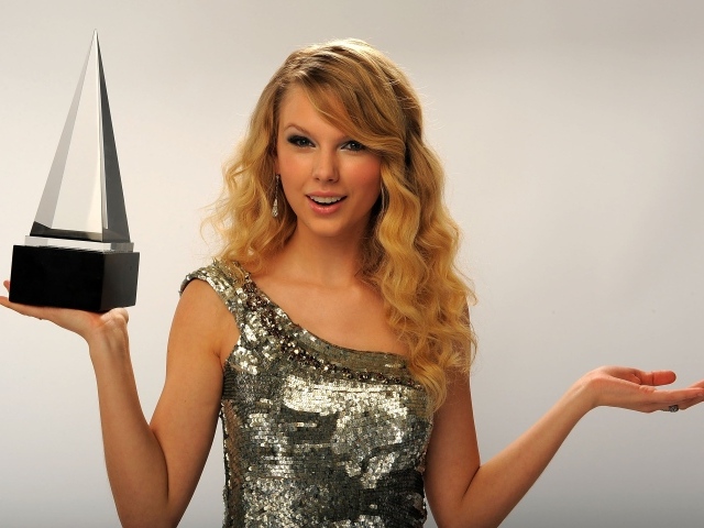 Красивая блондинка певица Тейлор Свифт с наградой в руке 