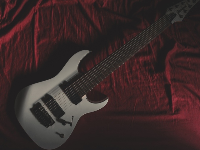 Гитара лежит на красном покрывале