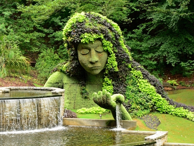 Красивый водопад в парке со скульптурой 