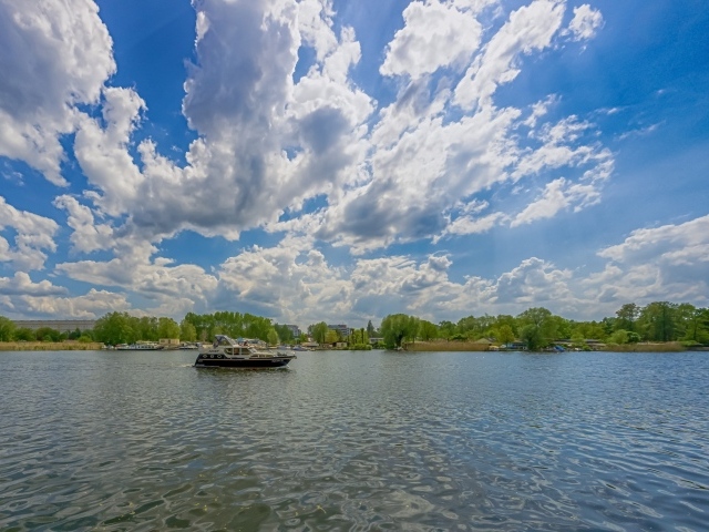 Катер на озере под красивым голубым небом с белыми облаками