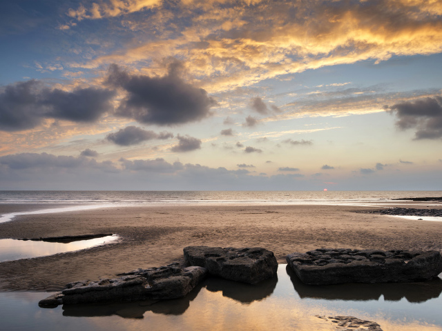 Большие камни в воде на песке под красивым небом