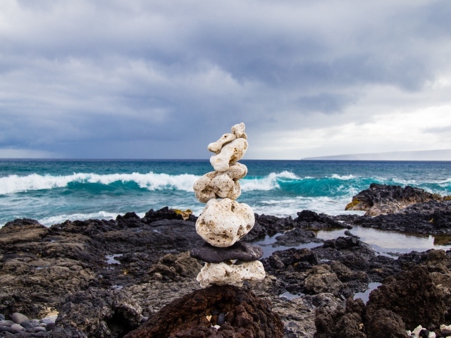 Пирамида из камней у моря на фоне пасмурного неба