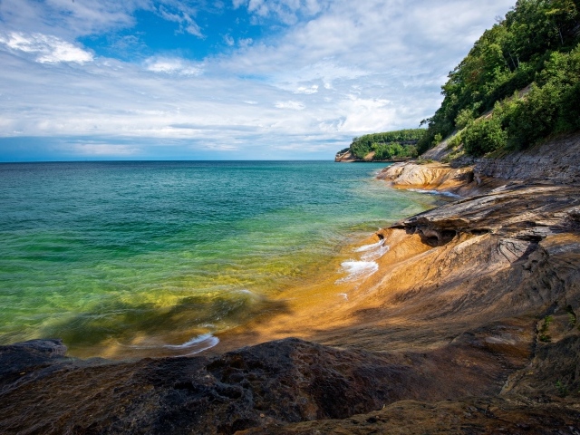 Скалистый берег у голубой воды моря на фоне неба
