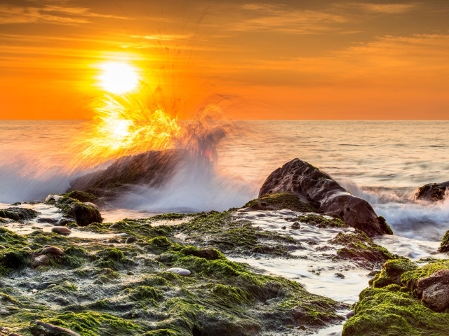 Бушующие волны в море бьются об камни на закате