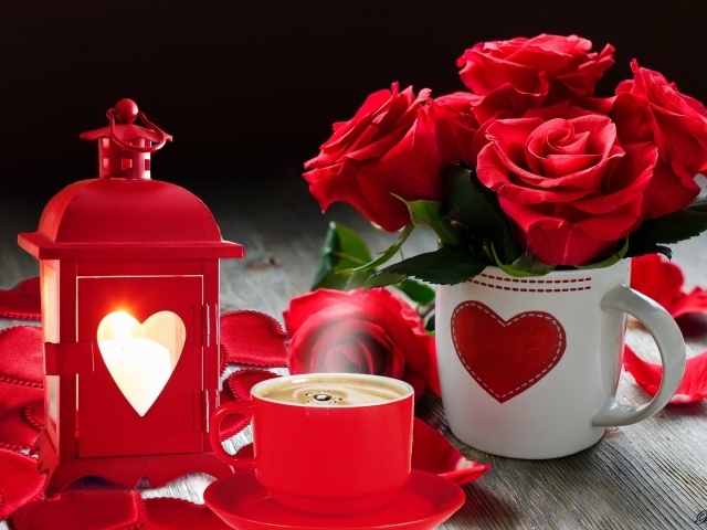 Букет красных роз в чашке на столе с фонариком и чашкой кофе