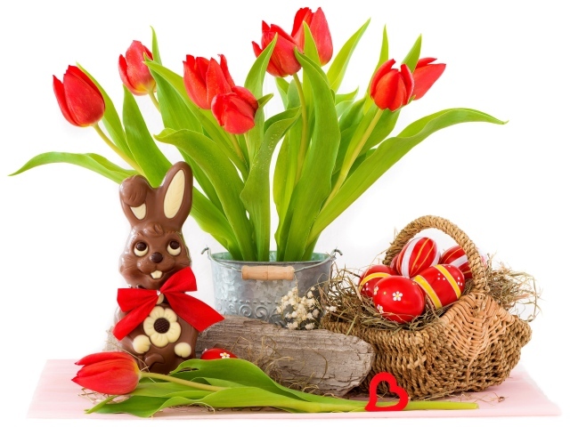 Букет красных тюльпанов на столе с шоколадным кроликом и крашеными яйцами на Пасху