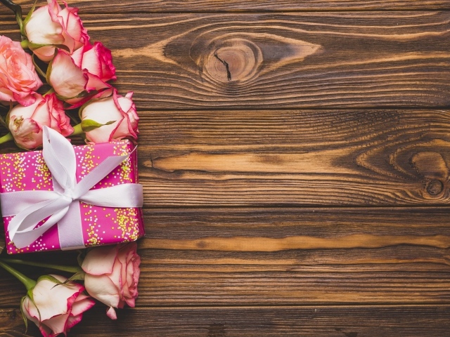Подарочная коробка с букетом роз на деревянном фоне 