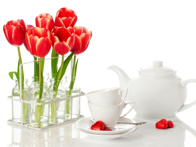 Красные тюльпаны с чайным сервизом на белом фоне