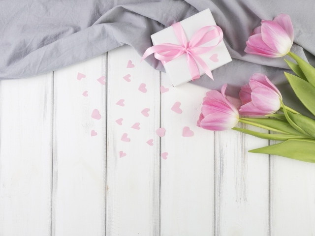 Три розовых тюльпана на столе с подарочной коробкой 