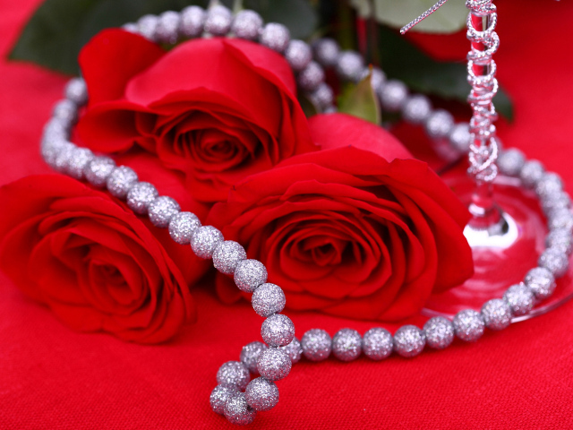 Три красные розы с украшением на красном фоне