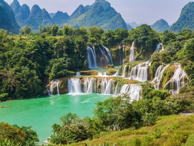 Водопад стекает с гор на фоне зеленой природы