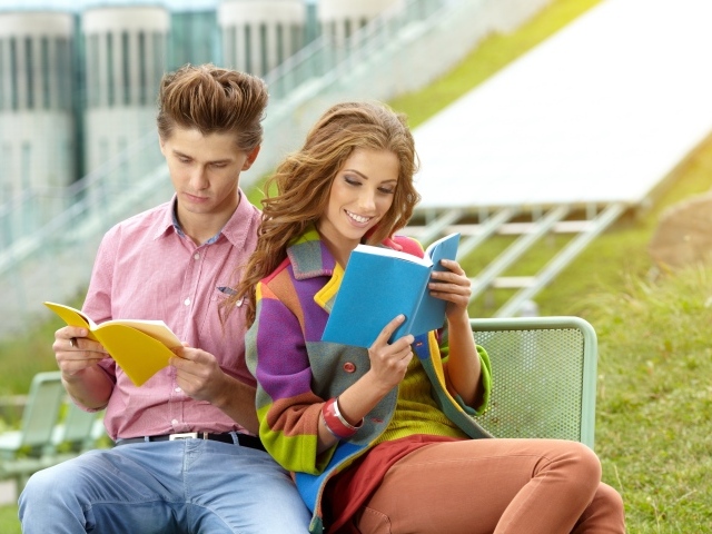 Парень и девушка читают книги сидя на лавке