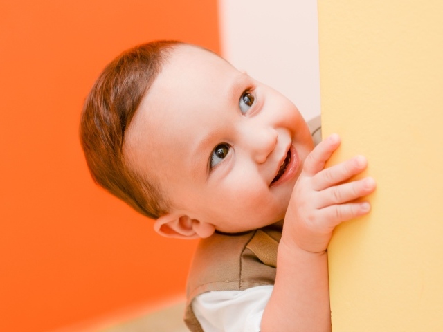 Маленький любопытный мальчик выглядывает из-за стены