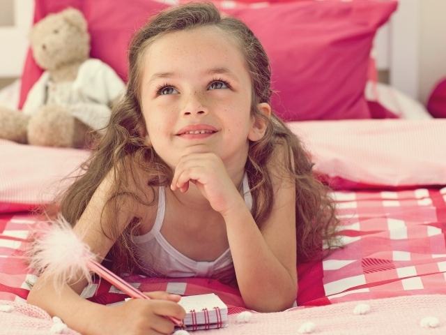 Замечтавшаяся маленькая девочка лежит на кровати