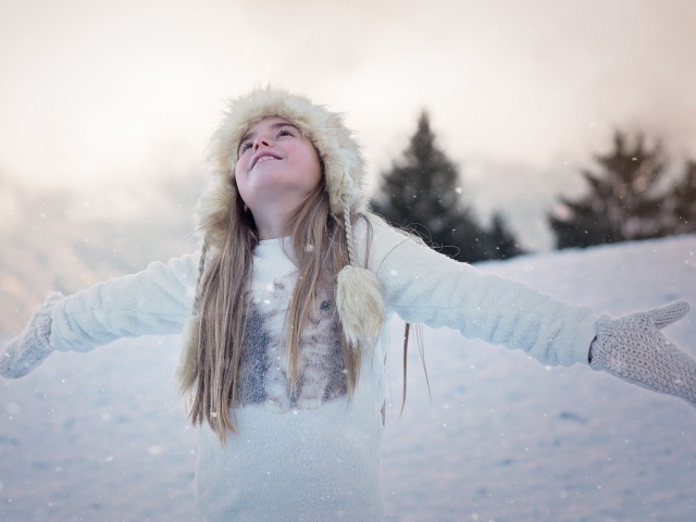 Девочка в белой шапке радуется снегу