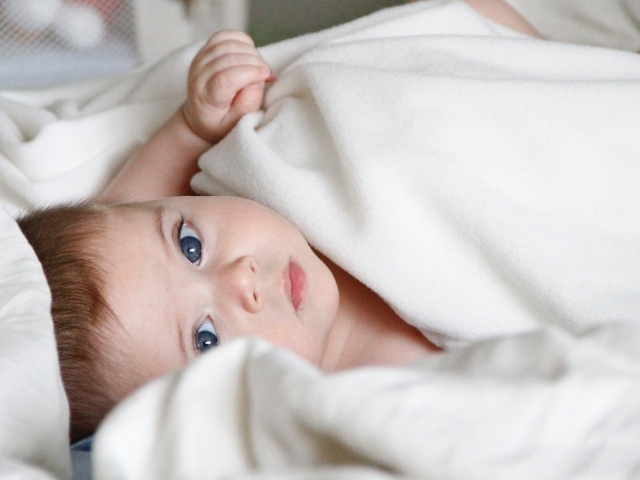 Маленький голубоглазый мальчик под белым покрывалом