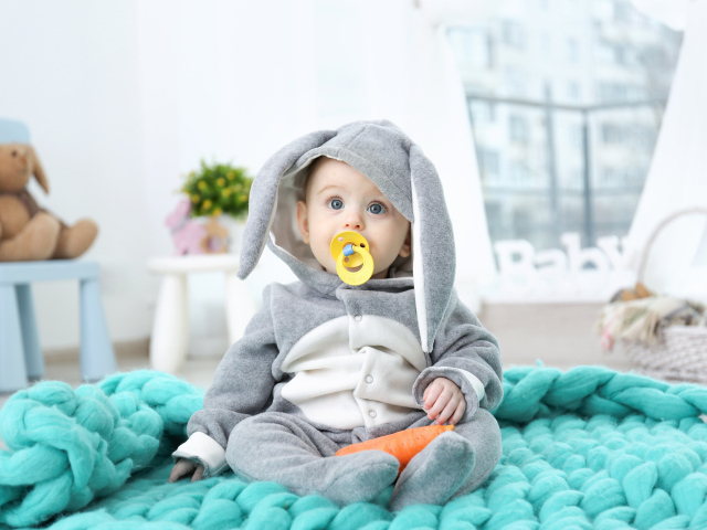 Маленький милый мальчик в костюме с пустышкой во рту