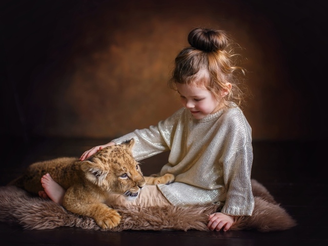 Маленькая девочка гладит маленького львенка