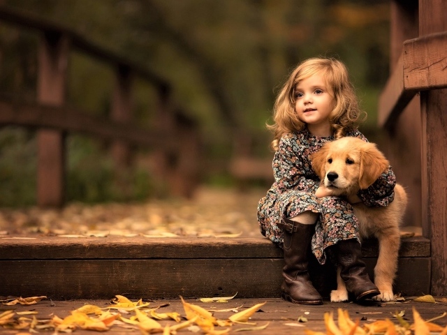 Маленькая девочка с золотистым ретривером сидит на мосту