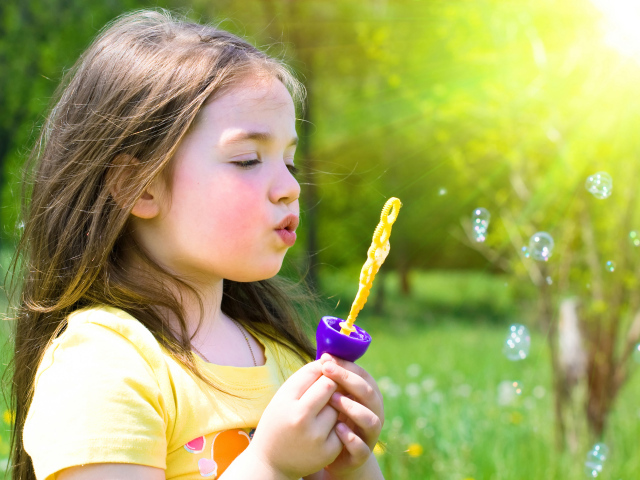 Маленькая девочка с мыльными пузырями в руках