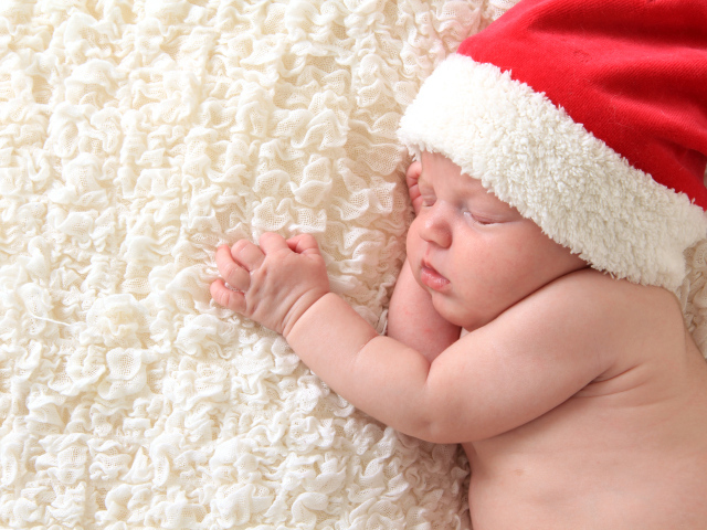 Маленький спящий ребенок в красном новогоднем колпаке