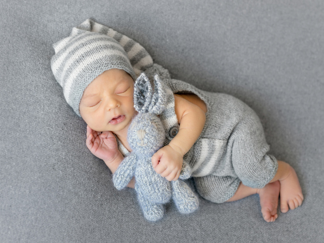 Спящий младенец с серым вязаным зайцем
