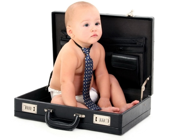 Маленький ребенок в галстуки сидит в кожаном дипломате