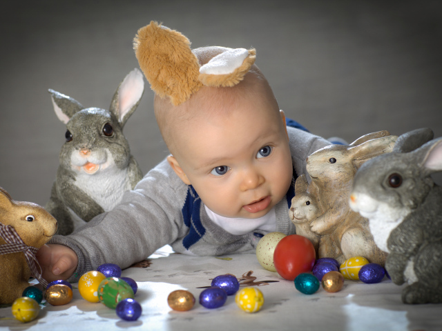 Маленький ребенок с пасхальными кроликами и яйцами