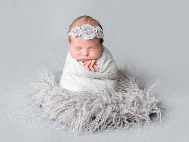 Маленький спящий младенец на сером фоне