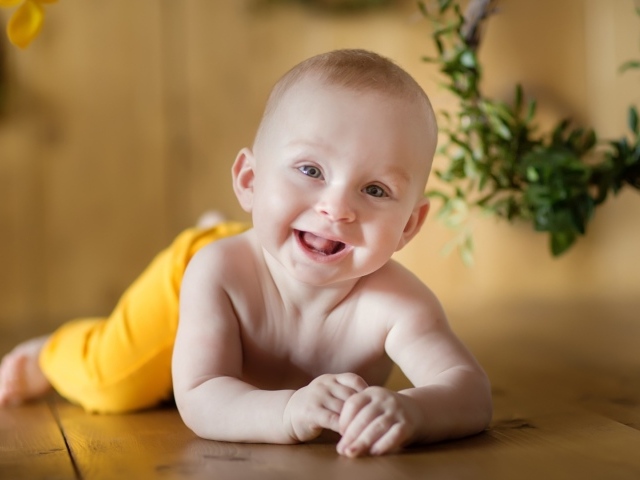 Улыбающийся малыш лежит на деревянном полу