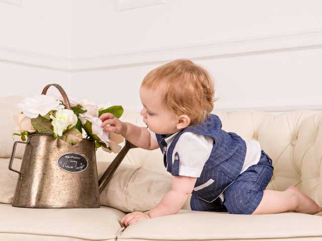 Маленький ребенок рассматривает цветы в железной лейке