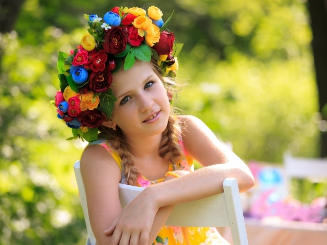 Красивая девочка с венком на голове сидит на стуле