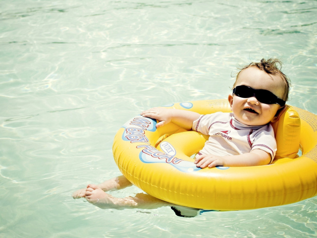 Веселый малыш на спасательном кругу в бассейне