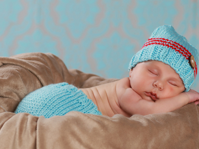 Забавный спящий младенец в голубом вязаном костюме 