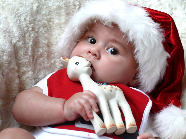 Маленький ребенок в новогодней шапке с игрушкой в руке